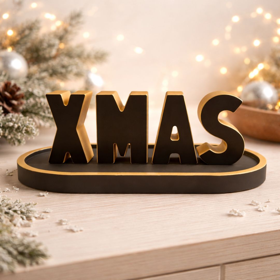 Buchstaben X-MAS mit schwarzer ovaler Platte und Goldrand